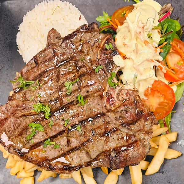 Grilled steak with rice, fries, and a fresh salad with creamy dressing, a Peruvian dish.