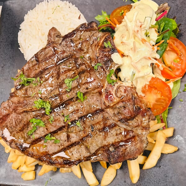 Grilled steak with rice, french fries, and a fresh salad with creamy dressing.