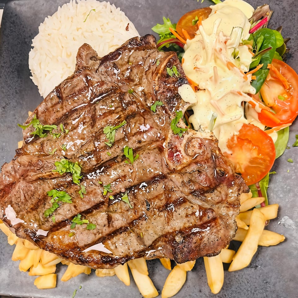 Grilled steak with rice, french fries, and a fresh salad with creamy dressing.