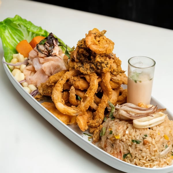 Peruvian seafood platter with fried calamari, ceviche, rice, and a shot of leche de tigre.