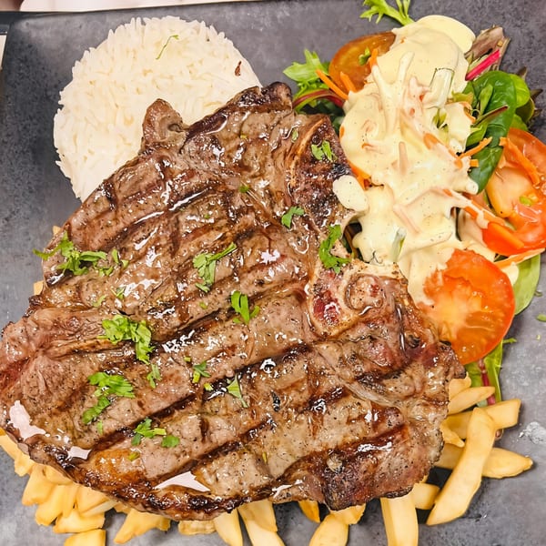 Peruvian grilled steak with rice, french fries, and a fresh salad with creamy dressing.