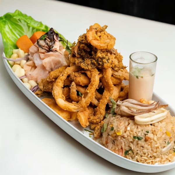 Peruvian seafood platter with fried calamari, ceviche, rice, and a shot of leche de tigre.